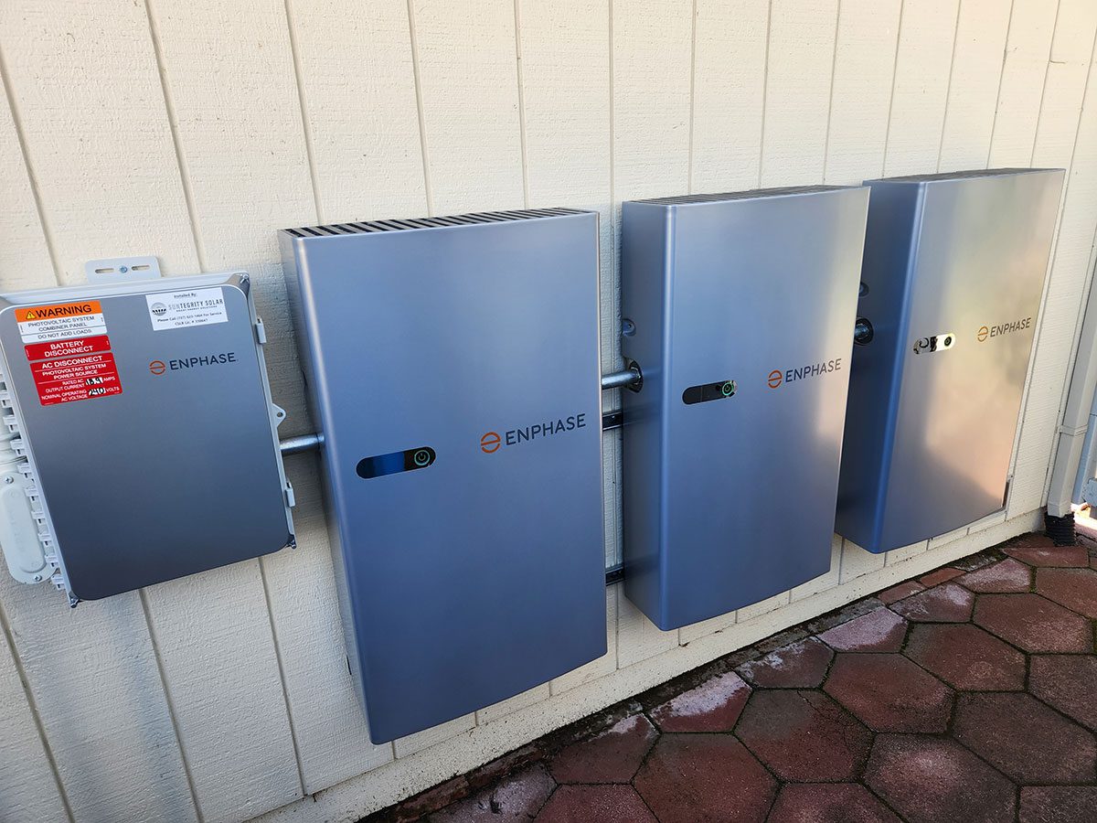 energy-storage1 Three Enphase energy storage battery units and an electrical box, part of a Santa Rosa solar battery energy storage setup, are mounted on an exterior beige wall above red hexagonal pavers.